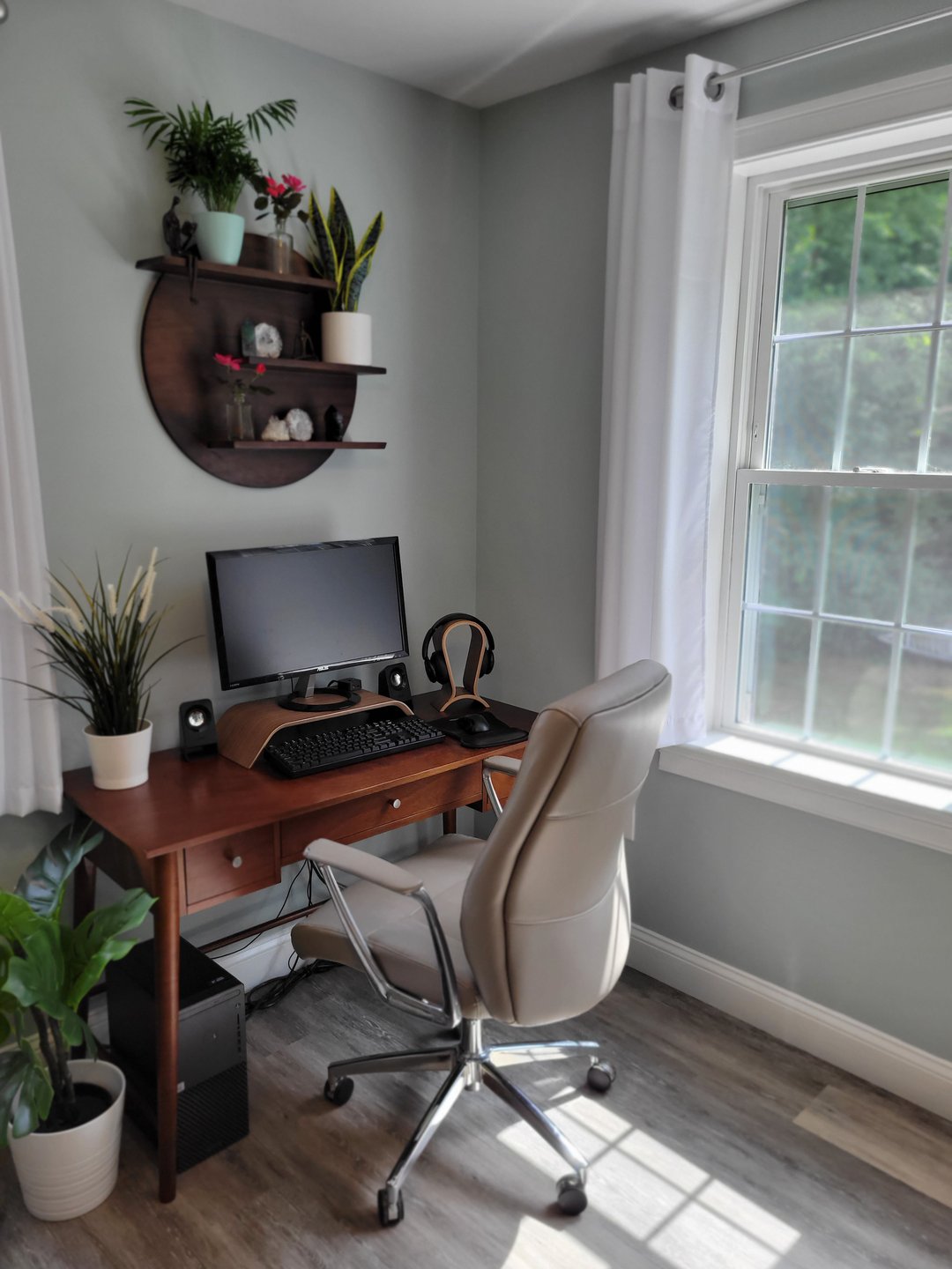 This photograph shows the author's desk next to a window. Everything is clean and simple. The gray walls, white curtains, and a few potted plants give an air of calm and peace.