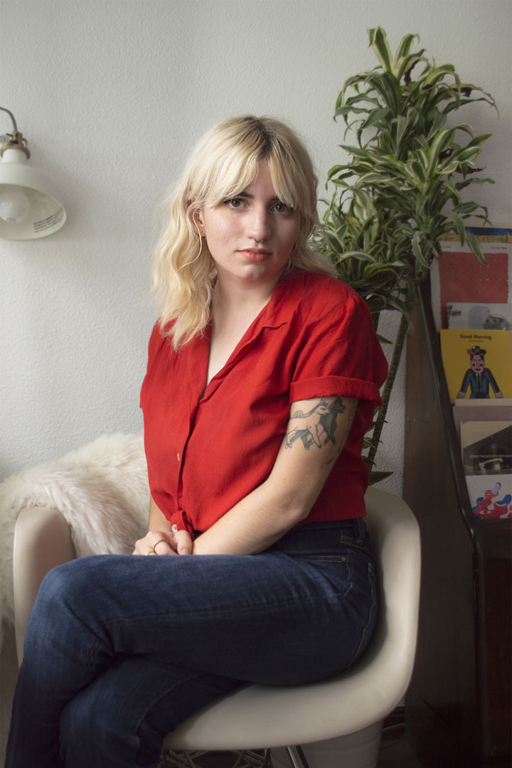 Photo of Celia Jacobs in a bright red button-down shirt and jeans in her beautiful, minimalist work space.