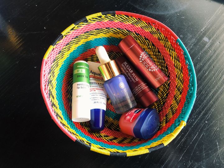 This photograph shows a colorful wire bowl filled with an assortment of different lip balms
