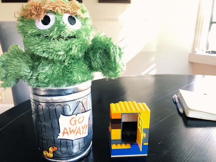 This picture shows a stuff Oscar the Grouch and his trash can next to a small lego structure
